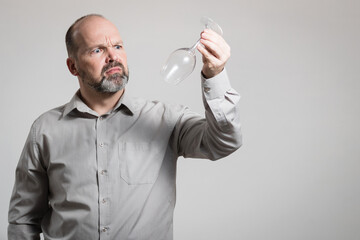 Caucasian man staring at empty wine glass, white background. Conceptual image of The Dry Challenge - Powered by Adobe