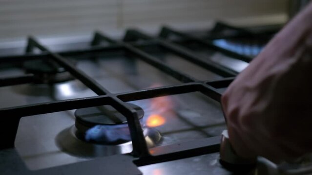 Person hand turns on kitchen cooktop gas burner and natural gas ignites burns with blue flame and then turned off.