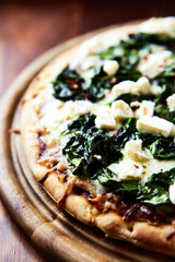 Pizza with mozzarella cheese and spinach. Dark wooden background. Close up.	