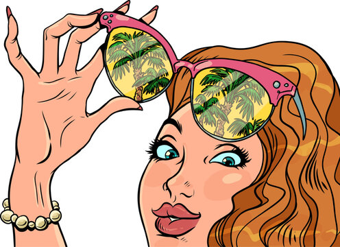 Rest on vacation, vacation. A womans hand with a manicure holds sunglasses, and her face looks at the palm trees. Reflection in glasses.