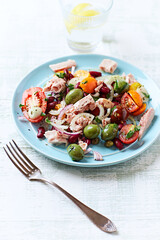 Salad with tuna, green olives and cherry tomatoes. Bright wooden background. Close up. Copy space.