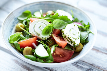 Summer Salad with Cream Cheese, green Olives, Tomatoes and fresh Basil. Bright wooden background. Close up	