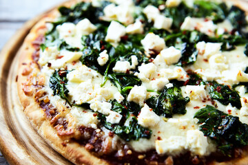 Pizza with mozzarella cheese and spinach. Dark wooden background. Close up.	