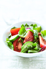 Simple Salad with Tomatoes, Cucumber and fresh Basil. Bright wooden background. Close up. Copy space. 