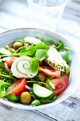 Summer Salad with Cream Cheese, green Olives, Tomatoes and fresh Basil. Bright wooden background. Close up	