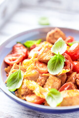 Farfalle pasta with chicken breast, cherry tomatoes and fresh basil. Bright wooden background. Close up.	