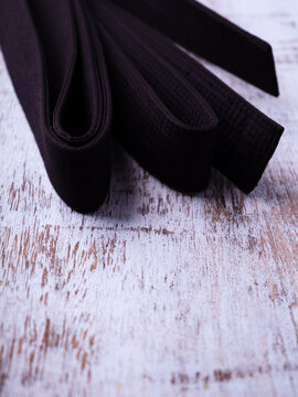 Black karate belt on rustic wooden background.