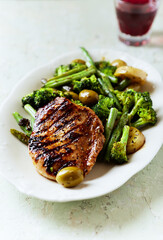 Grilled Turkey Breast with oven baked potatoes and broccoli. Bright wooden background. Close up.