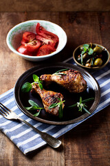 Spicy chicken drumsticks with fresh herbs. Close up.	