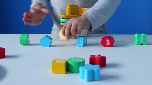 A little boy stacks plasticboats inside one another, with wooden numbers laid out on the table. This activity aids in developing fine motor skills and learning to count. child development