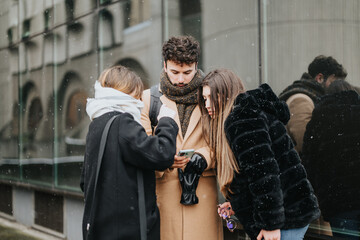 A group of young business colleagues gather outside on a snowy day, engaged in conversation with a...