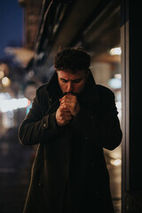 A stylish and good-looking businessman standing on a busy city boulevard at night, smoking a...