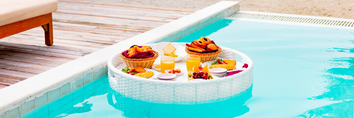 served floating tray in swimming pool with drinks and snacks on tropical island resort in Maldives, breakfast for romantic date or honeymoon in luxury hotel, travel concept