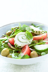 Summer Salad with Cream Cheese, green Olives, Tomatoes and fresh Basil. Bright wooden background. Close up.
