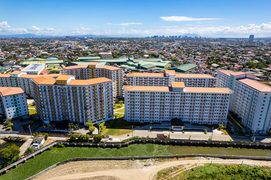 Sucat, Paranaque, Metro Manila, Philippines - High angle shot capturing a cluster of apartment buildings with the city skyline in the background on a clear day.