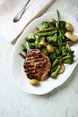 Grilled Turkey Breast with oven baked broccoli and green olives. Bright wooden background. Top view.	