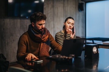 A team discuss project details for market research and financial analysis in meeting at office. A woman warms her hands by breathing into them.