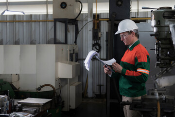 worker in factory.  worker checking list work in factory. engineer in hand hold folder list order on machine background.
