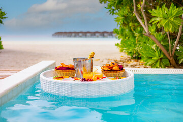 Fototapeta na wymiar served floating tray in swimming pool with drinks and snacks on tropical island resort in Maldives, breakfast for romantic date or honeymoon in luxury hotel, travel concept