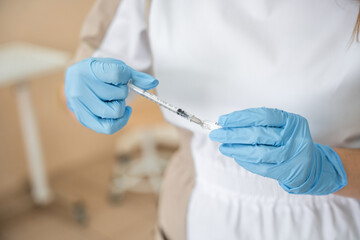 Close-up of d doctor's hand filling vaccine syringe