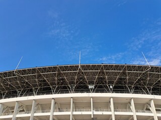 Architectural photo of part of a football stadium with blue sky in the background.	