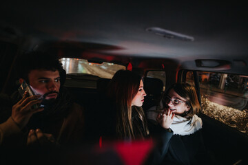 A candid shot capturing a moment of intense discussion among three young adults in the backseat of a car, illuminated by ambient city lights.