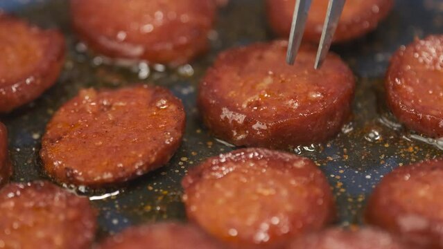 Cooking Turkish Sausage Also Known as Sucuk in Pan. Unrecognizable Person Flipping Sliced Meats to Roast Perfectly. Preparing for Breakfast Close Up Shot Slow Motion. Camera Moving Left to the Right. 