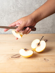 pears are peeled using a hand knife, on a wooden table placed on a white plate