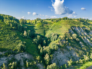 The steep bank of the river is densely overgrown with forest and bushes, a view from a height of...