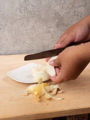 pears are peeled using a hand knife, on a wooden table placed on a white plate