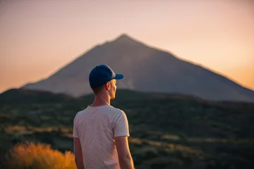 Foto auf Acrylglas Kanarische Inseln Rear view man looking at landscape with Teide volcano at sunset. Tourist during hike on Canary island of Tenerife..