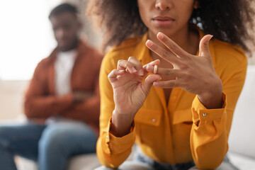 black woman taking off wedding ring sitting near husband indoors