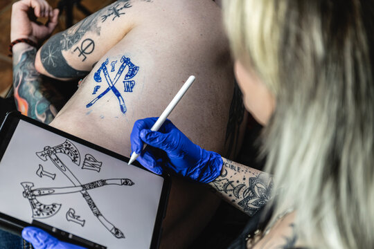 Horizontal photo tattoo artist checking with the tablet a design on skin. Concept business, art.