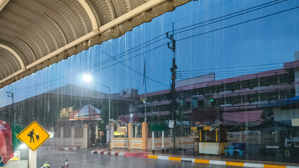 Raining on street in front of school in evening time, perspective side view from roadside area