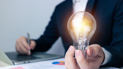 Business idea concept.Businessman touch light bulb to idea investment and calculating with...