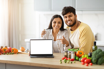 Beautiful loving spouses making food, watching video content on laptop - obrazy, fototapety, plakaty