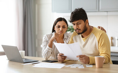 Upset young indian couple paying bills online