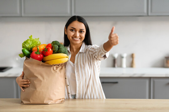 Happy young hindu woman with paper bag full of grocery