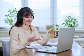 Girl teenage student in headphones having video chat online on computer