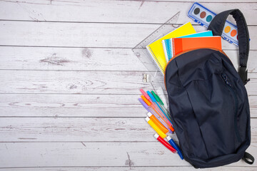 BACKPACK WITH SUPPLIES ON WOODEN TABLE. BACK TO SCHOOL.
