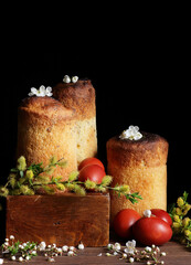 Homemade easter cakes with spring flowers, fresh willow bouquet and red eggs on dark moody rustic background, traditional russian holiday food, cottagecore aesthetics, slow living celebration concept