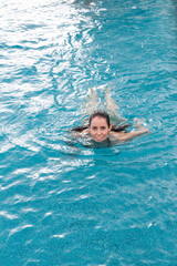 Woman swimming in pool looking at camera