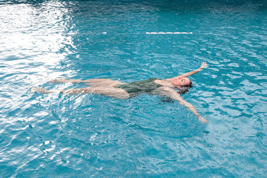 Woman enjoying a relaxing swim in the swimming pool, floating