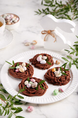 Easter chocolate shortbread cookies in a shape of nest filled with colorful egg candies. Delicious homemade festive food. Selective focus.