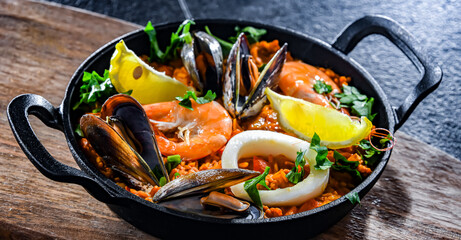 Seafood paella served in a cast iron pan - obrazy, fototapety, plakaty
