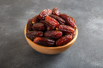 Date fruits in wooden bowl,on black background.Top view
