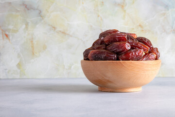 Date fruits in wooden bowl,in front of bright background