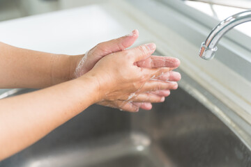 Close up woman hand washing under running water in the kitchen.Hygiene and cleaning hands.Image...