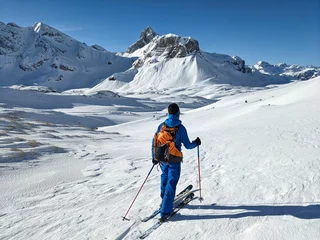 Fotobehang Ski mountaineer runs through a beautifully snowy mountain landscape in Glarus Schwyz. Ski tour on the Pfannenstock. Ski mountaineering in the Swiss Alps. Ski touring in winter. High quality photo © SimonMichael