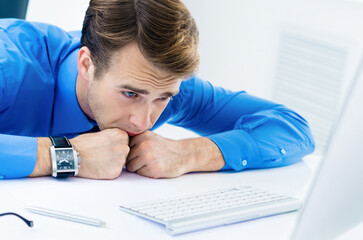 Naklejka premium Portrait image - shocked, distraught or tired, unhappy business man in confident blue shirt, working with computer at office. Business, job and education concept.